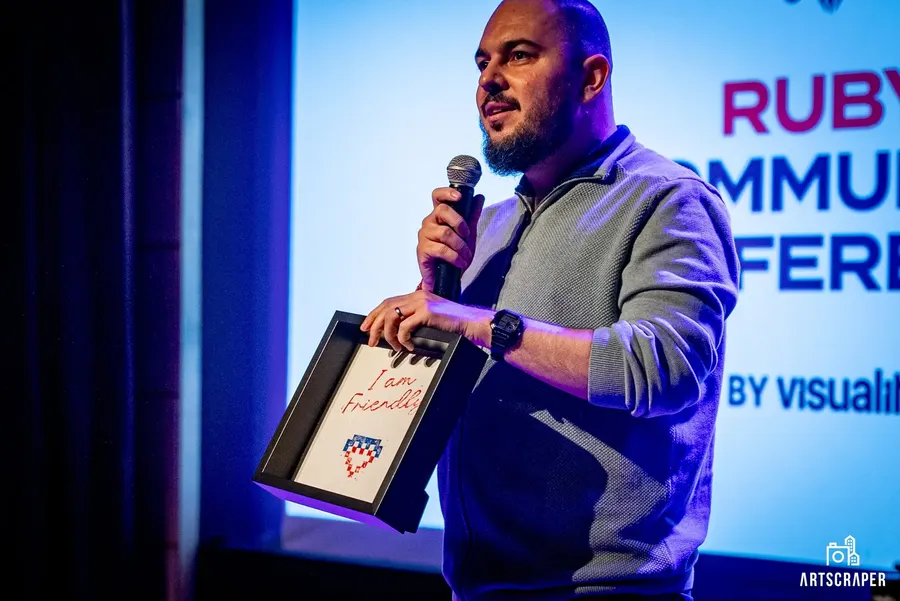 A speaker on stage in front of the Ruby Community Conference screen